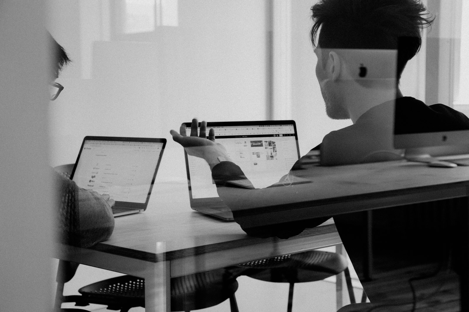 Two marketers reviewing work on laptops